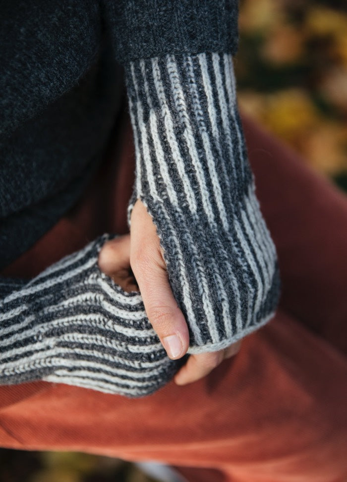 Rhona Gloves: gray and white striped fingerless gloves worn with red pants.
