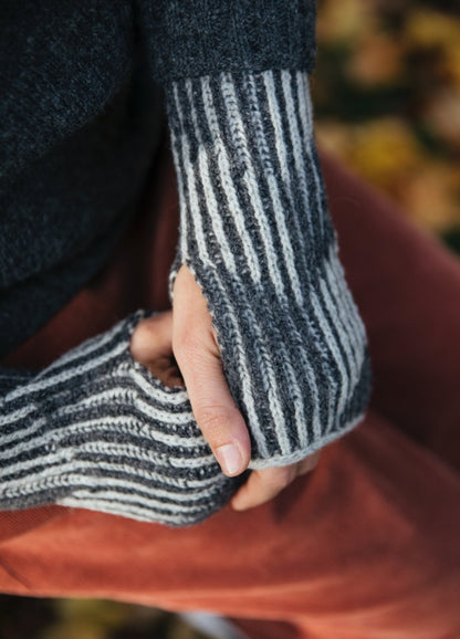 Rhona Gloves: gray and white striped fingerless gloves worn with red pants.