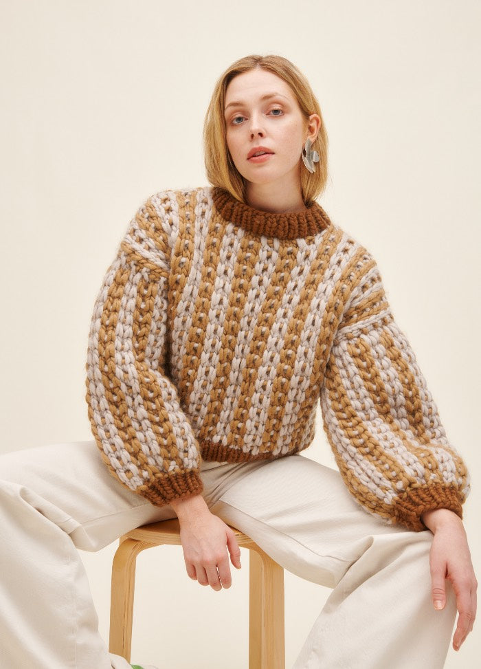 Snow and Tell Sweater: chunky striped knit in brown and cream with balloon sleeves, worn seated with light pants.