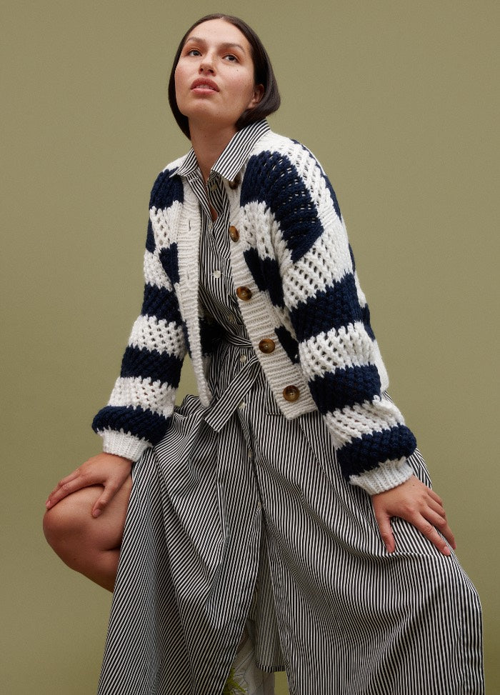 Ceto Cardigan: striped knit in white and dark blue with wooden buttons, layered over a vertically striped black and white dress.