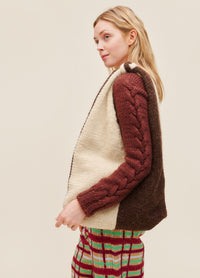 Bottari Bag: brown and white knit bag held by a model in a maroon cable sweater and colorful plaid pants.