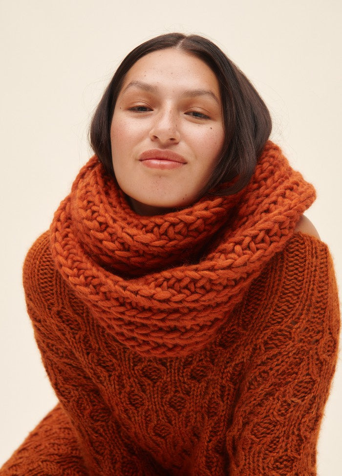 Ingrid Cowl: orange knit cowl paired with a matching sweater against a plain light background.