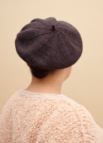 Koket Beret: dark beret worn over a bun with a light textured sweater, viewed from the back