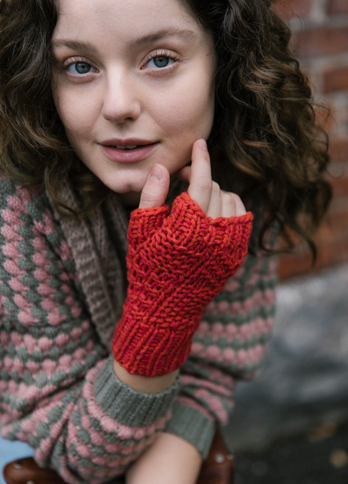 Vaapukka Mitts: red fingerless mitts worn with a pink and green patterned sweater