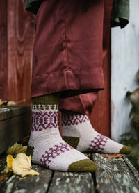 Boyland Socks: green, purple, and beige patterned socks worn with red pants, standing on wooden surface with fallen leaves