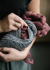 Hestia Slippers: gray textured knitted slippers with pink wool lining, held and adjusted by hands