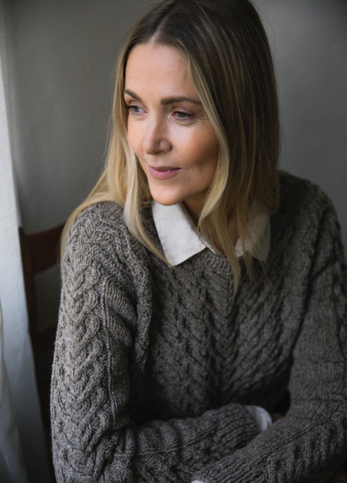 Lempi Sweater: grey cable-knit worn over white collared shirt, featuring intricate wool texture.