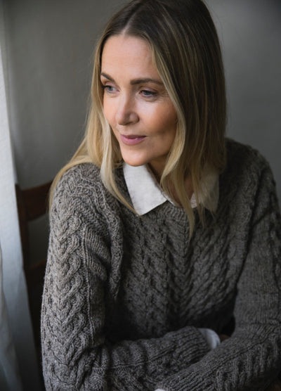 Lempi Sweater: grey cable-knit worn over white collared shirt, featuring intricate wool texture.