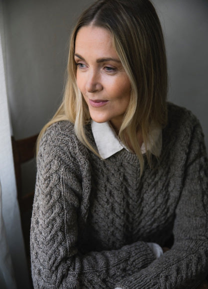 Lempi Sweater: grey cable-knit worn over white collared shirt, featuring intricate wool texture.