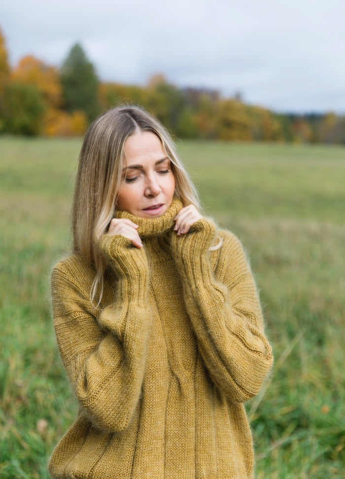 Ridge Forrester Sweater: mustard cable-knit worn outdoors in grassy field with trees.