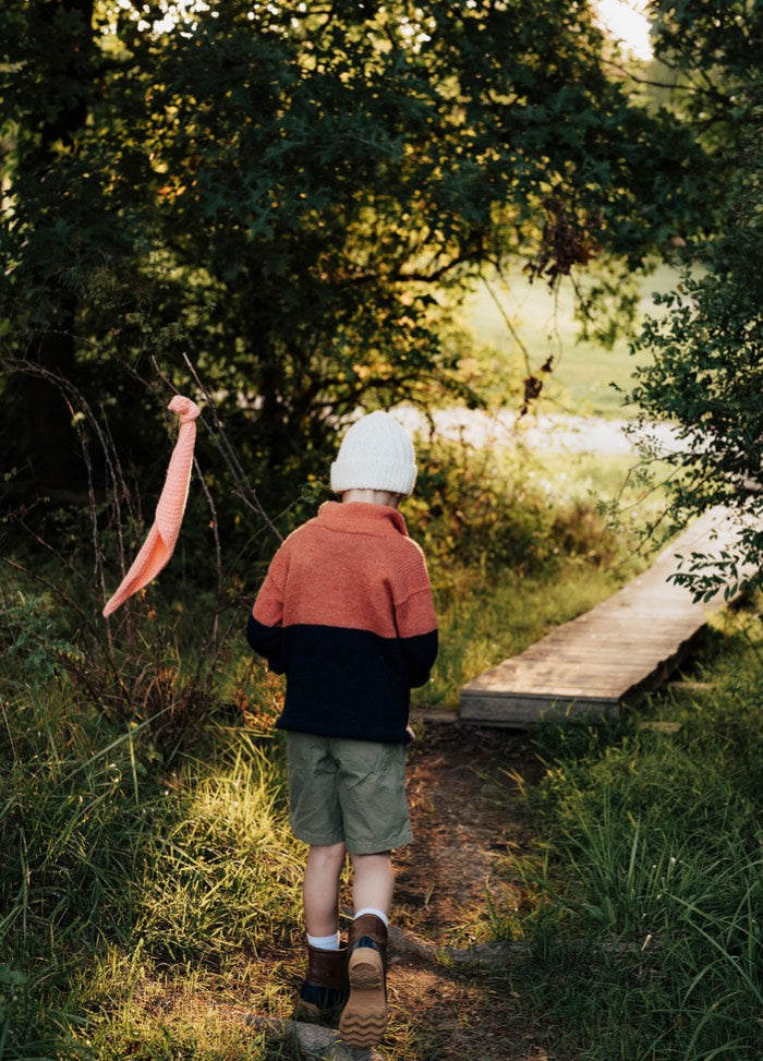 Brown and red pullover worn outdoors at sunrise, seated cross-legged on a blanket with a steaming cup.