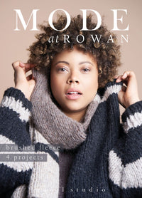 Woman wearing a cozy, oversized knitted scarf and sweater with a neutral background. The mood is warm and inviting, highlighting winter fashion.