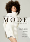 A confident woman with an afro hairstyle wears an oversized white turtleneck sweater, showcasing "MODE Collection Nine" for hand-knit designs by Rowan.