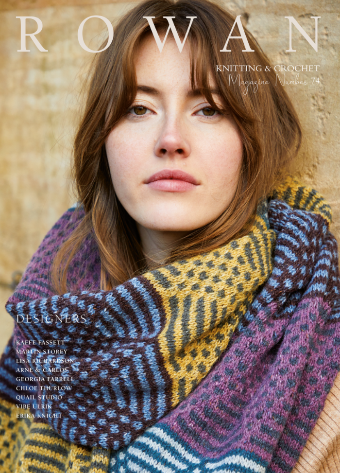 Young woman with long brown hair wearing a colorful, patterned knitted scarf. The background is a warm-toned textured wall. Text reads "Rowan Knitting & Crochet Magazine."