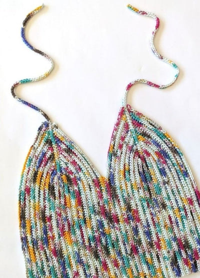 Crochet multicoloured top with a ribbed pattern, featuring vibrant hues of blue, yellow, and red. The ties are loosely coiled above.