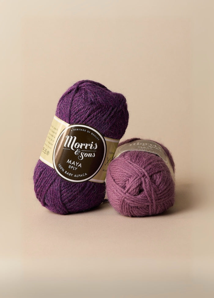 Two purple yarn balls labeled 100% baby alpaca, highlighting their softness and suitability for those sensitive to wool.