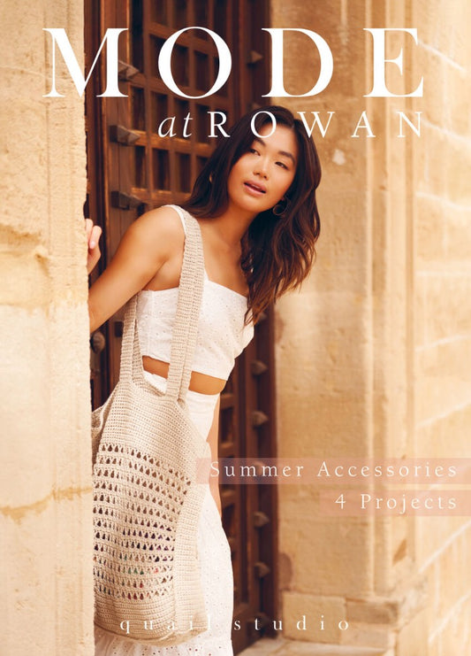 Woman in a white summer outfit leans against a textured stone wall, holding a crochet bag. The sunny, relaxed scene features the text "Mode at Rowan" and "Summer Accessories 4 Projects."