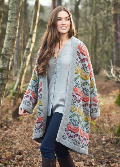 Woman strolling in autumn woods, wearing a colorful knit cardigan with floral patterns, blue jeans, and brown boots. She exudes a sense of serene contentment.