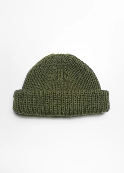 A green knitted beanie with a thick, folded brim is centered on a plain white background, conveying a simple, cozy, and minimalist feel.