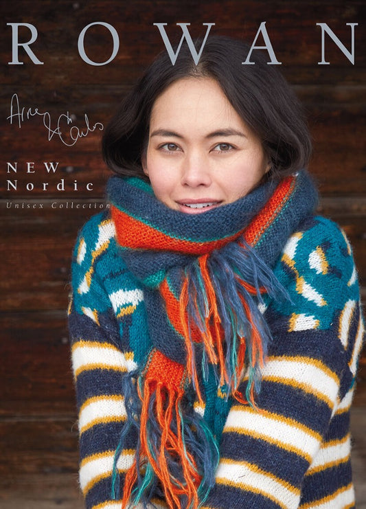 Woman in a colorful, cozy winter scarf and striped sweater, smiling gently. Rustic wood backdrop. Text reads "ROWAN New Nordic Unisex Collection."