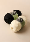 Two balls of Morris Brand yarn, 100% wool, perfect for crafting homewares or slippers, shown with labels in a rustic setting.
