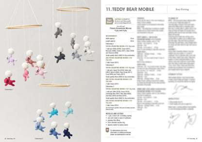 A mobile with small knitted teddy bears in pastel colours, hanging from wooden rings against a plain background. Instructions are blurred on the right. Keywords: knitting, mobile, teddy bears.