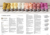 Seven pairs of knitted baby socks with animal face designs in gradient colours from yellow to pink, displayed above a blurred knitting pattern. Tone: playful.