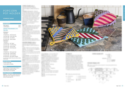 Colorful crocheted pot holders with popcorn stitches sit on a kitchen counter next to a mug and kettle. Cozy and handmade vibe.