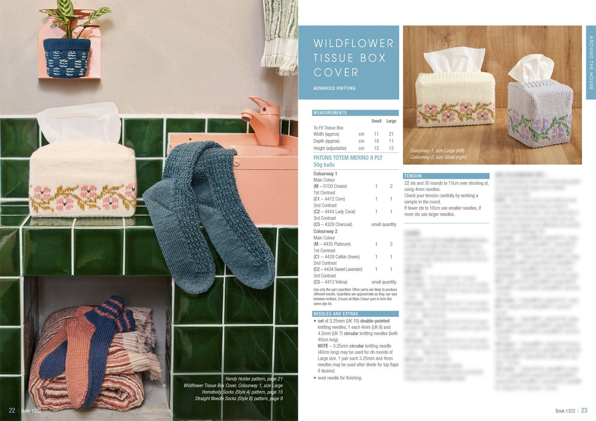 A cozy bathroom scene shows knitted items: a floral-patterned tissue box cover, blue and orange socks, and folded towels. The instruction page on the right lists knitting details. The mood is warm and inviting.