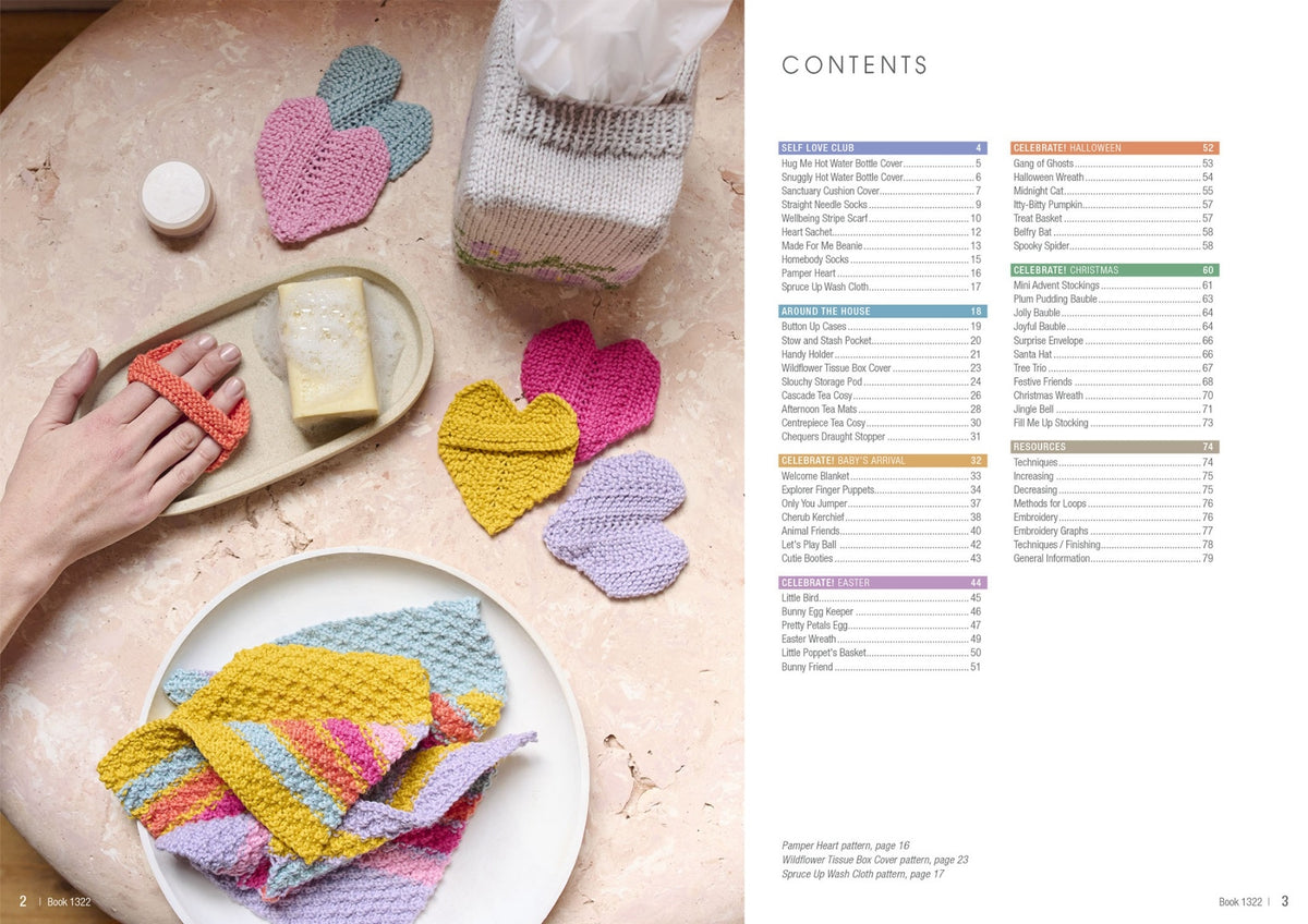 A flat lay of knitted accessories on a pale marble surface, including a hand holding an orange knitted soap holder with a bar of soap, a tissue box covered in a grey knitted cozy with small flower motifs, and heart-shaped knitted coasters in pink, yellow, and purple. A plate in the foreground holds folded pastel-striped knitted cloths. The right side of the image shows a contents page listing patterns under categories like Self Love Club, Around the House, Celebrate Baby’s Arrival, and more.