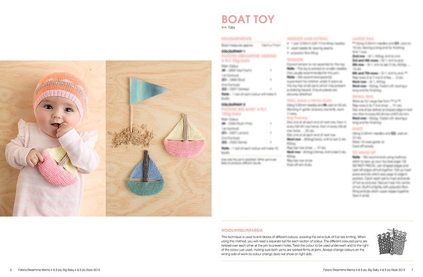 A baby in a pastel outfit holds a knitted pink boat toy, lying on a wooden surface with two more colorful boat toys and a flag. The opposite page contains text and instructions titled "Boat Toy." The scene is playful and cozy.