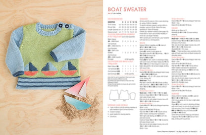 Hand-knitted baby sweater with sailboat design on a light wood background, next to small paper boats and sand. Instructions labeled "Boat Sweater."