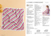 A colorful, striped knitted blanket lies flat, featuring pink, yellow, and blue diagonal lines. On the right, blurred text describes knitting instructions.