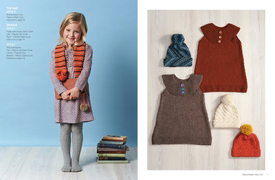 A smiling girl in a purple dress, gray tights, and an orange scarf stands beside stacked books. Next to her are laid-out knit dresses and hats.