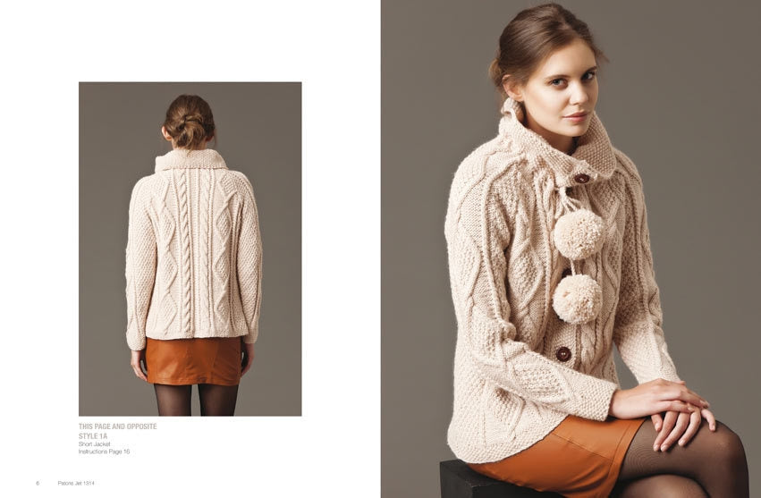 A woman in a cozy cream knit sweater with pom-pom accents sits on a stool. She pairs it with a brown skirt. The mood is warm and stylish.