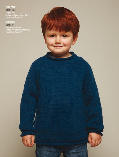 A child with red hair wearing a blue knitted sweater stands against a neutral background, smiling gently. The sweater style is detailed on the left.