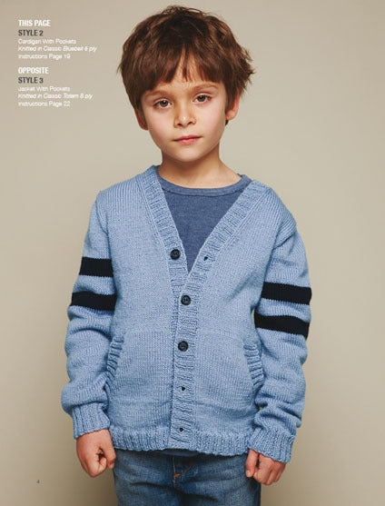 A young child with brown hair wearing a light blue cardigan with dark blue stripes on the sleeves. The child stands against a plain background.