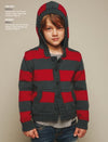 Young child wearing a red and gray striped hooded cardigan with front pockets, buttons, and jeans stands confidently against a neutral background. Cozy and casual tone.