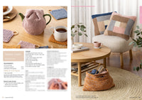 Cozy living room scene with a pink knitted tea cosy on a teapot, colorful coasters, a cup of tea, knitted pillows on a chair, and yarn in a basket. Warm and inviting ambiance.