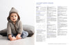 A baby wearing a striped hooded jacket and jeans sits on a soft cushion. Next to the baby, a page of knitting instructions titled "Jacket with Hood."