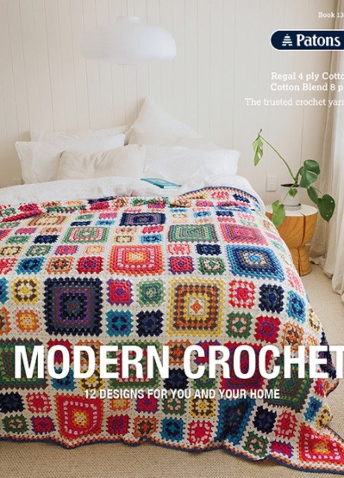 A cozy bed with colorful, geometric-patterned crochet blanket in a bright, minimalist bedroom. Text reads "Modern Crochet: 12 Designs for You and Your Home."