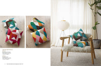 Colorful geometric cushions on a wooden floor, paired with a cozy chair. Natural light and a potted plant enhance the room's serene vibe.