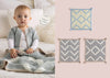 A baby wearing a light cardigan sits on a bed with a knitted blanket, conveying warmth and coziness. Next to the baby, three geometric knit squares are displayed.