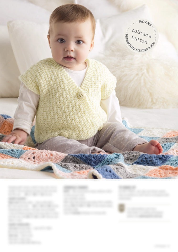 A baby sits on a colorful crocheted blanket, wearing a cream knitted vest and gray polka dot pants. The background is soft-focus, creating a cozy atmosphere.