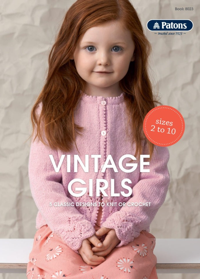A young girl with red hair smiles gently, wearing a pink knitted cardigan and a matching patterned skirt. Text reads "Vintage Girls: 5 Classic Designs."