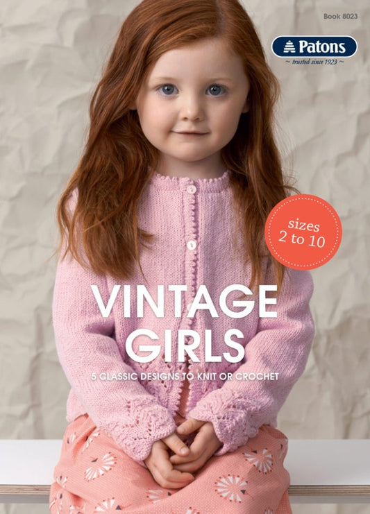 A young girl with red hair smiles gently, wearing a pink knitted cardigan and a matching patterned skirt. Text reads "Vintage Girls: 5 Classic Designs."