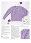 Lavender knitted sweater with textured sleeves, surrounded by purple and white felt flowers. Label reads "silky soft merino." Close-up detail shown.