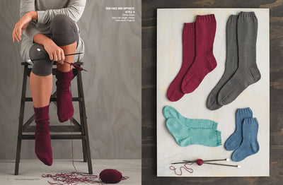 A person sitting on a ladder is knitting burgundy socks, with yarn and needles nearby. On the right, burgundy, gray, teal, and blue socks are displayed on a board.