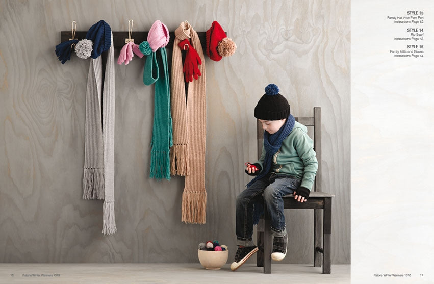 A child in winter clothes sits on a chair, holding a red toy. Colorful scarves and hats hang on the wall. The scene feels cozy and playful.