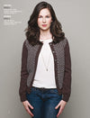 Woman with long brown hair wears a patterned brown cardigan over a white shirt and jeans, standing confidently against a gray background.